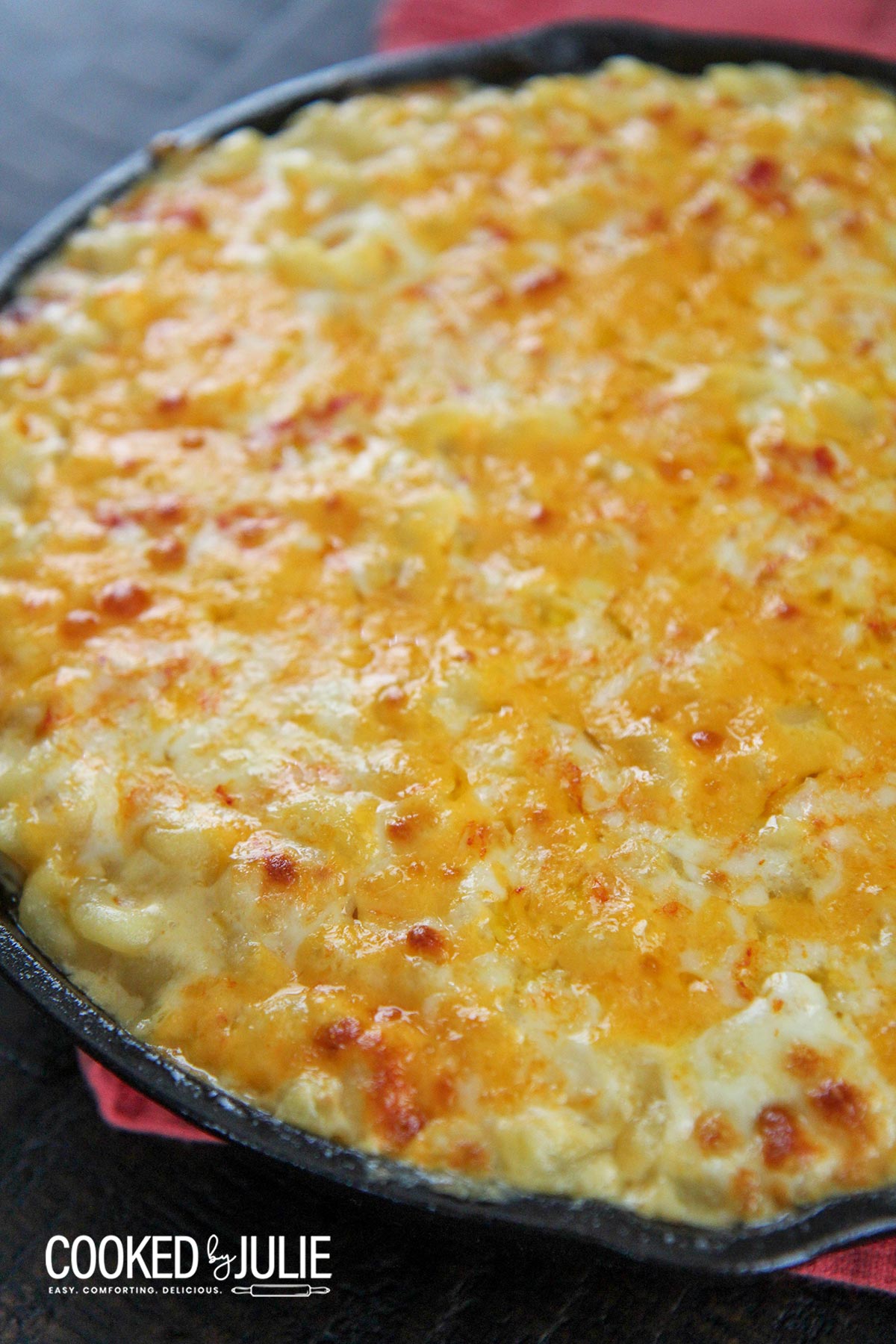 mac and cheese in an iron skillet with a red towel on the side