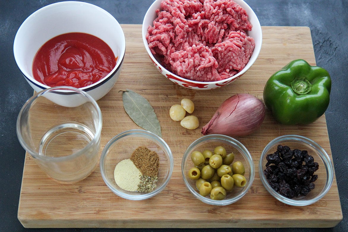 twelve ingredients in small bowls on a wooden board