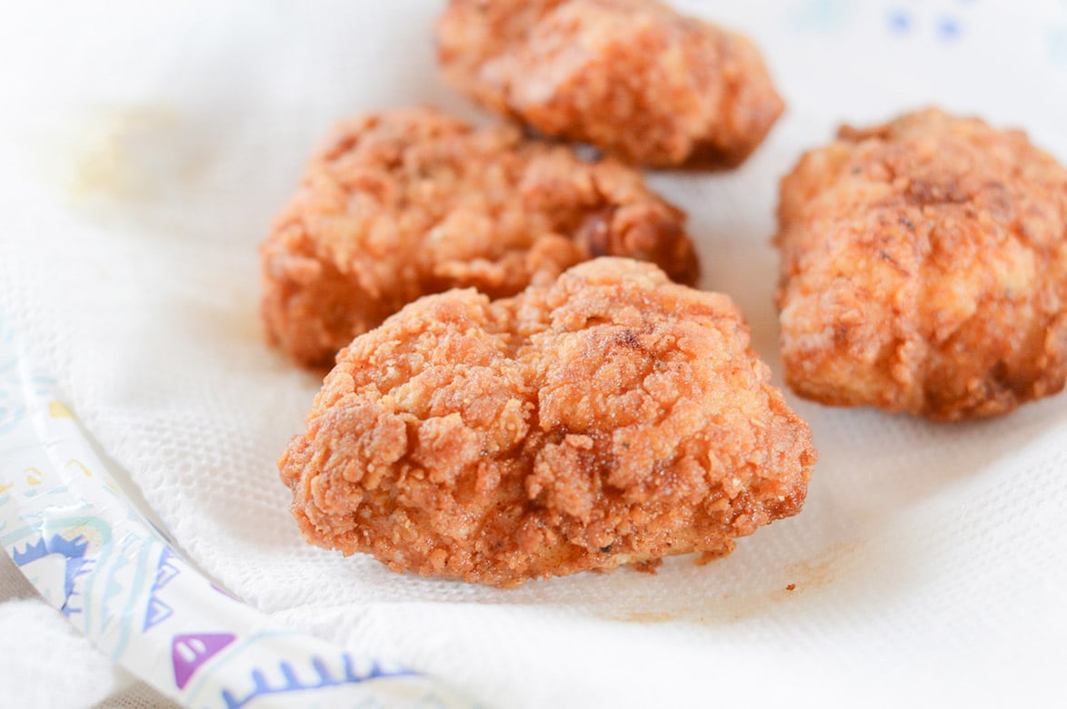 four crispy chicken sliders on paper towel 