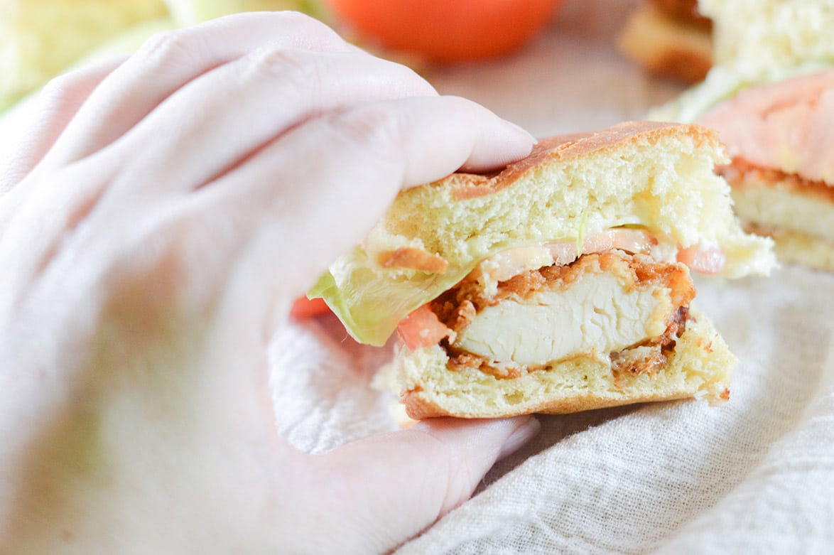 hand holding a half bitten chicken slider 