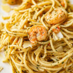 shrimp pesto spaghetti on a white plate up close.