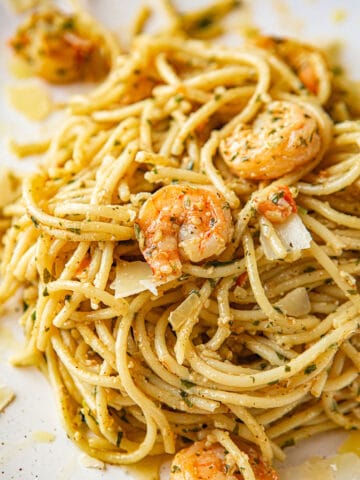 shrimp pesto spaghetti on a white plate up close.