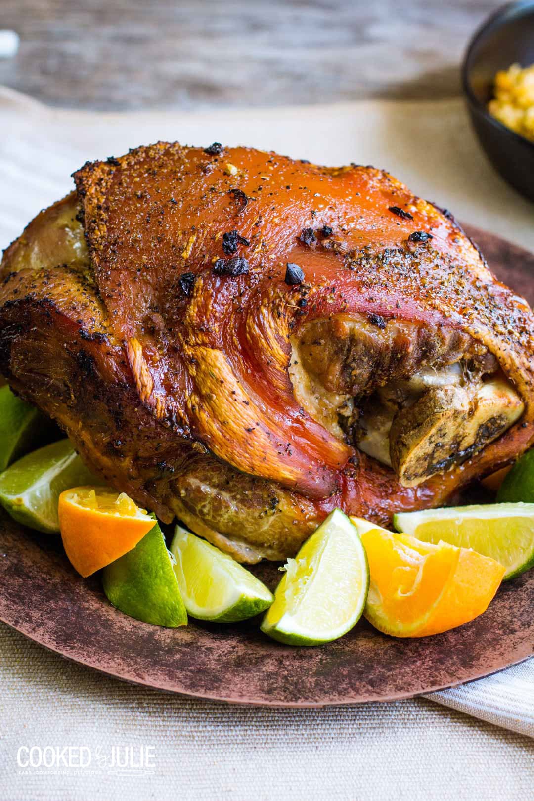 roasted pork on a brown plate with limes and oranges