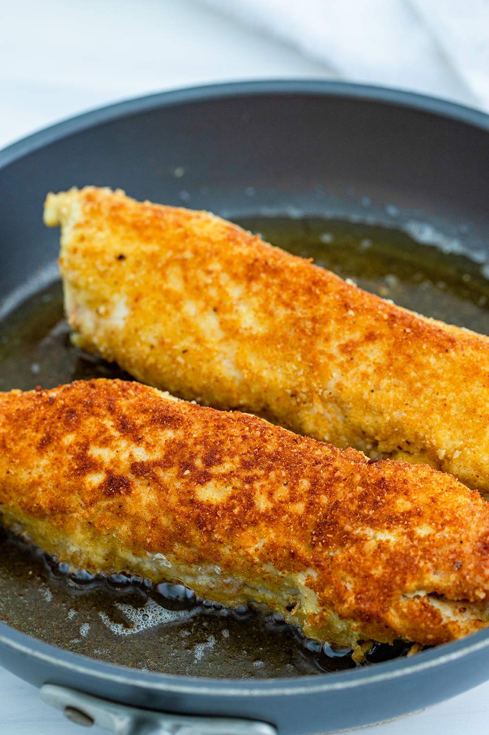 two chicken breasts rolled up and fried in a skillet.