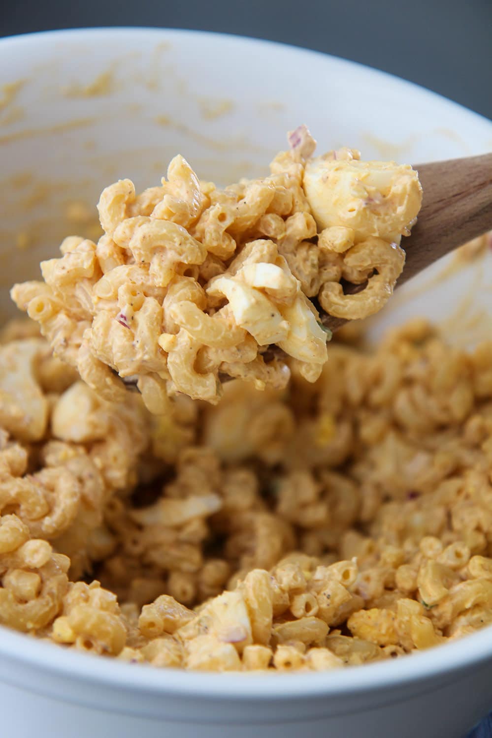 elbow macaroni with hard boiled eggs and a wooden spoon.