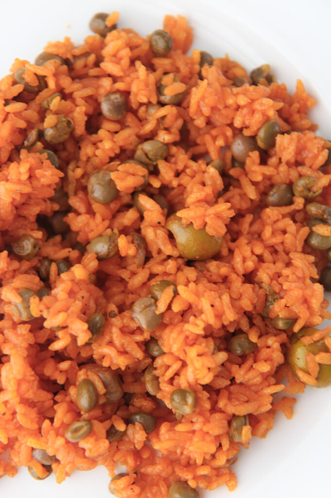 yellow rice with pigeon peas on a white plate up close.