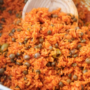 arroz con gandules in a large pot with a wooden spoon.