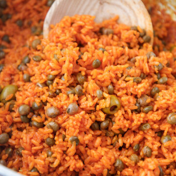 arroz con gandules in a large pot with a wooden spoon.
