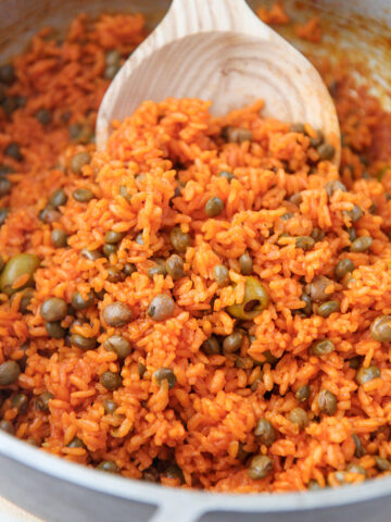 arroz con gandules in a large pot with a wooden spoon.