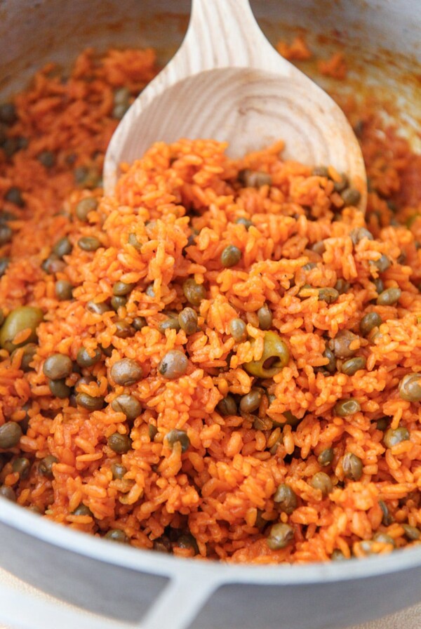 arroz con gandules in a large pot with a wooden spoon.
