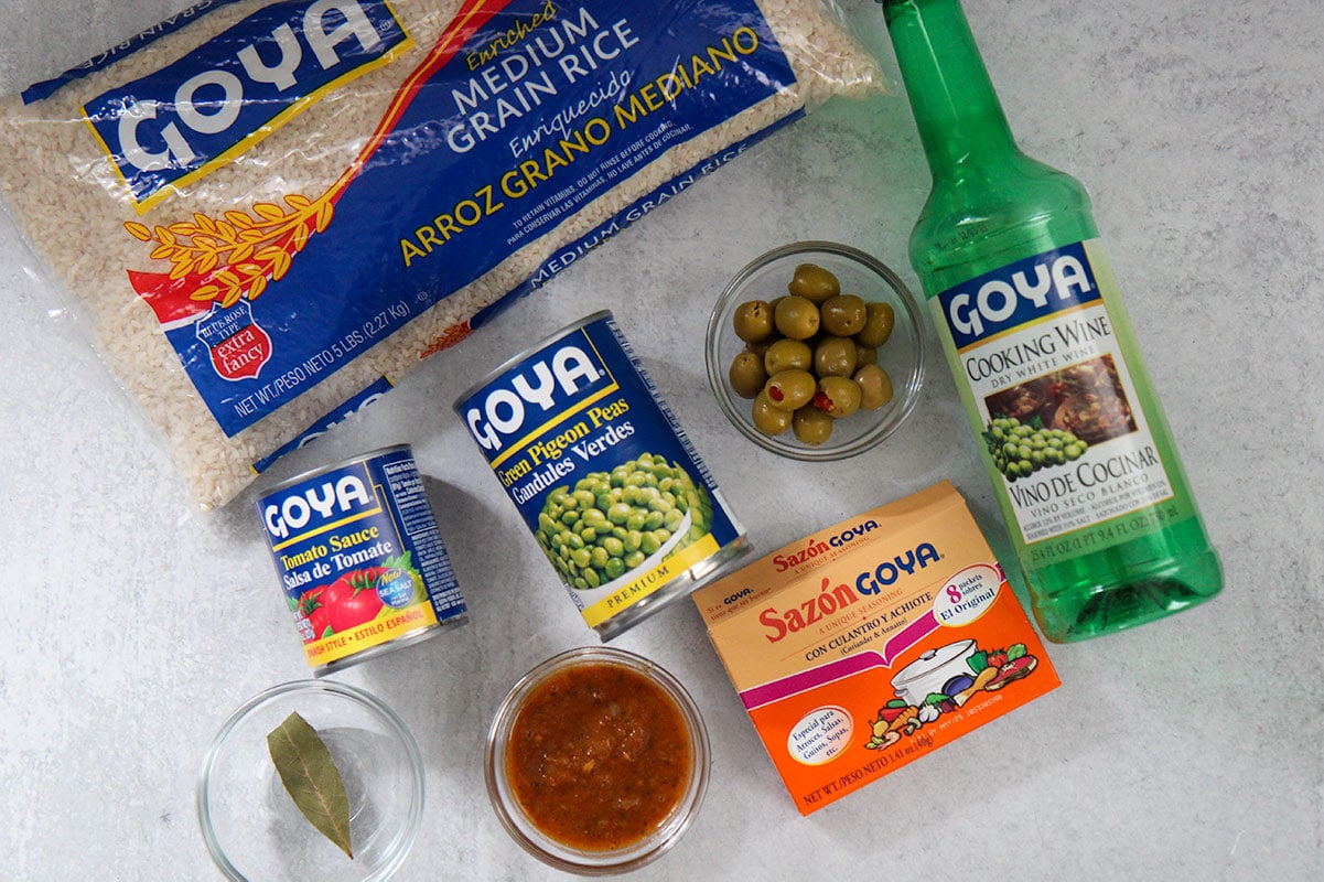 8 packaged ingredients including rice, olives, sazon, tomato sauce, sofrito, cooking wine, and a bay leaf.