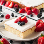 a slice of tres leches cake on a white plate with berries
