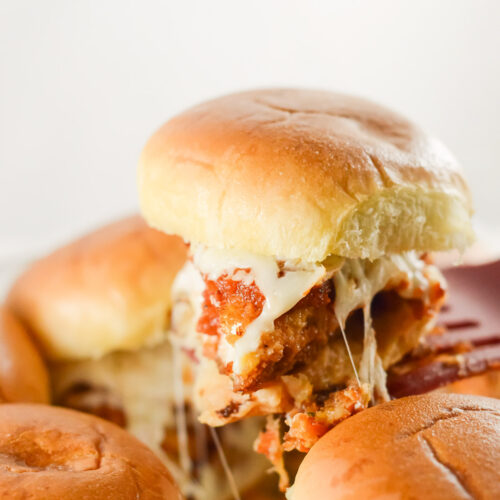 a spatula lifting a chicken parm slider from a the baking pan.