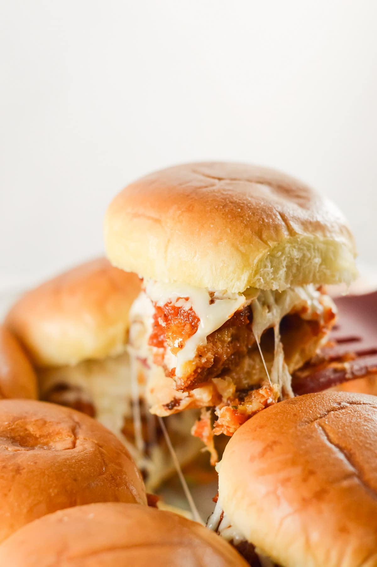 a spatula lifting a chicken parm slider from a the baking pan.
