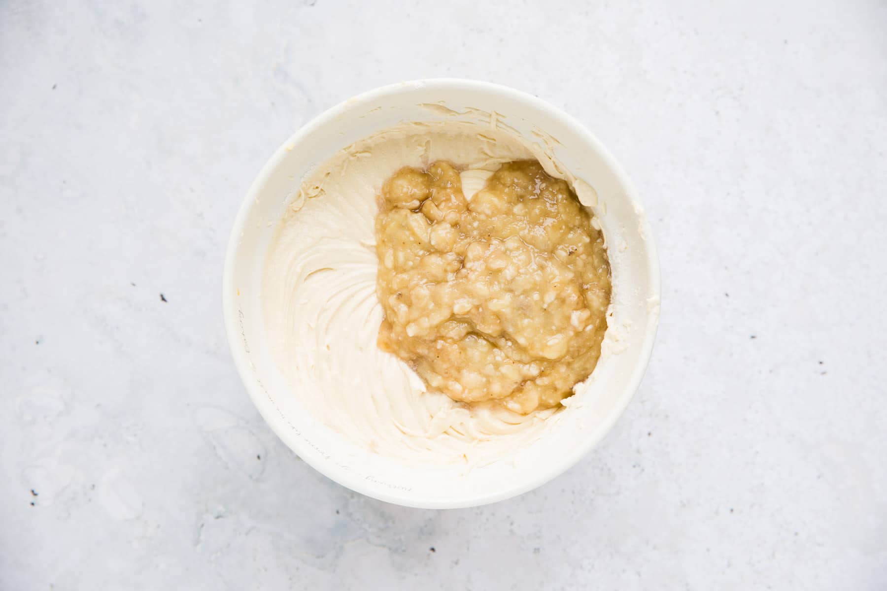 pureed banana and cake batter in a white bowl. 