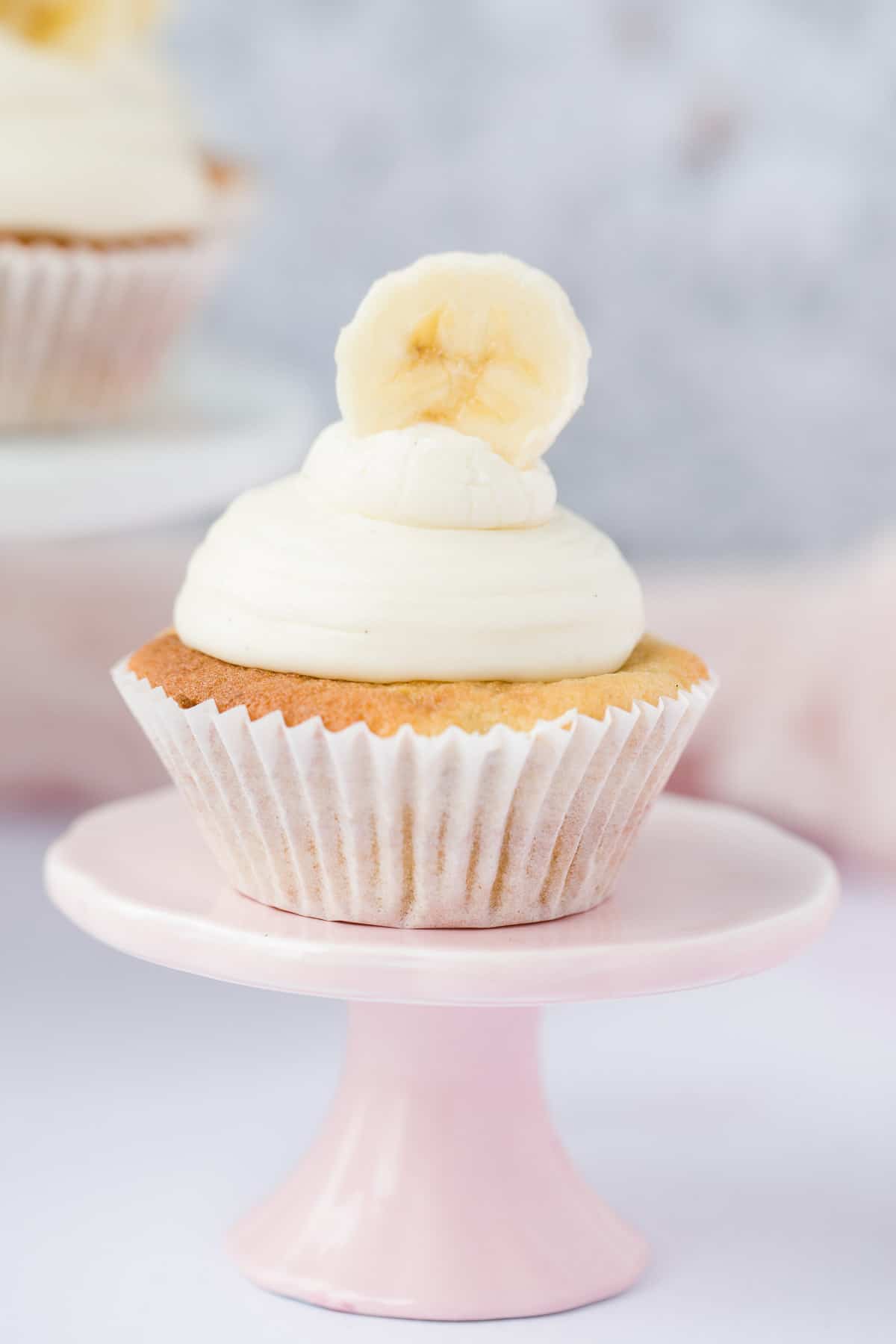 one banana cupcake on a small pink cake stand.