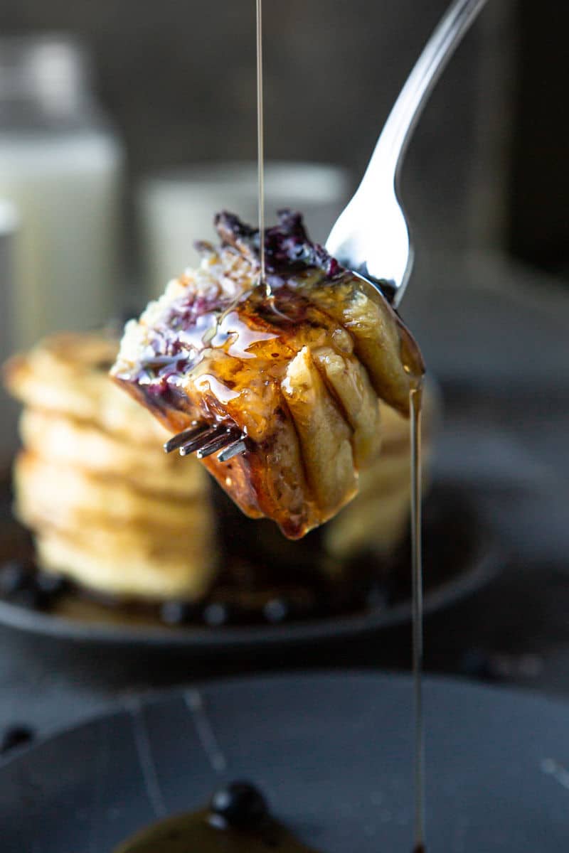 a fork holding four pieces of pancake with syrup on top.