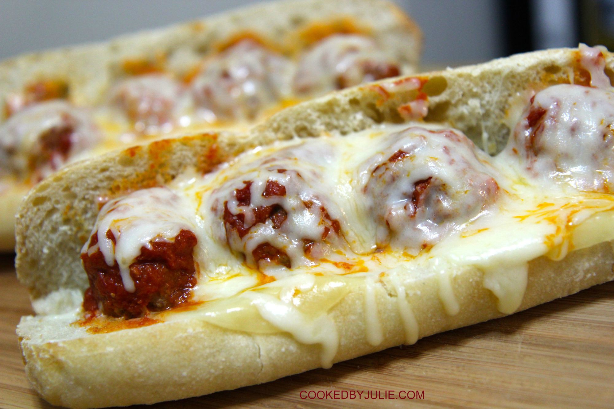 two meatball parmesan sandwich on a wooden board 