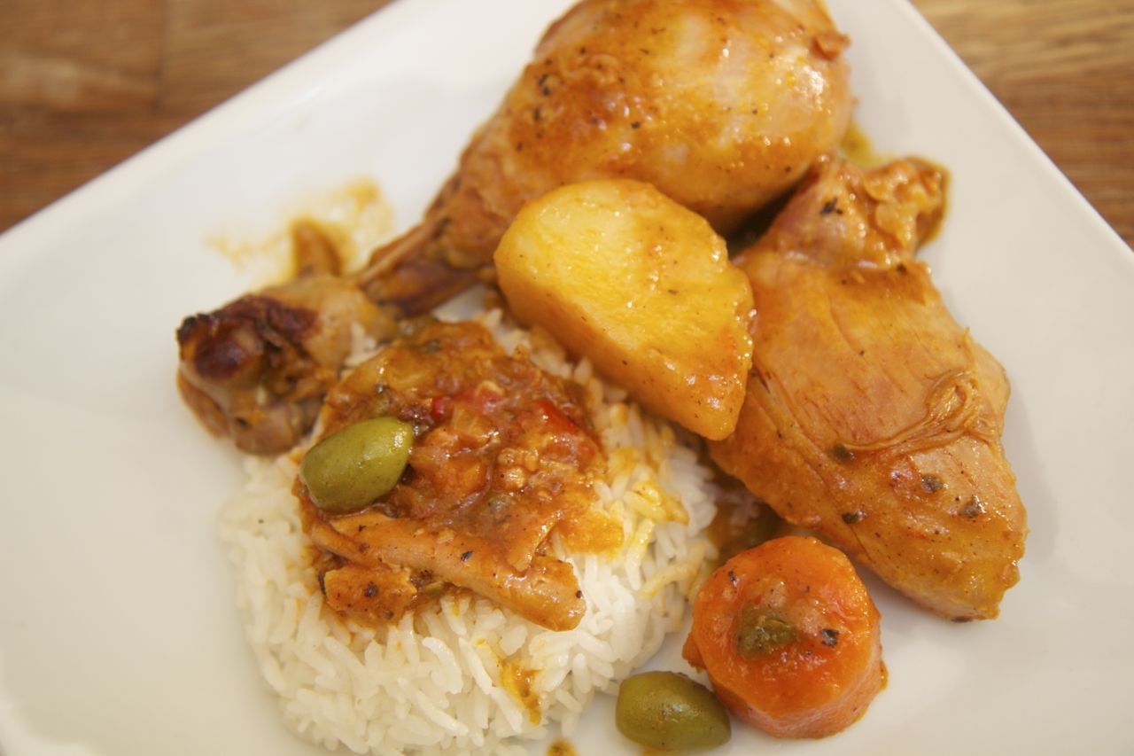 fricase de pollo over white rice on a white plate. 