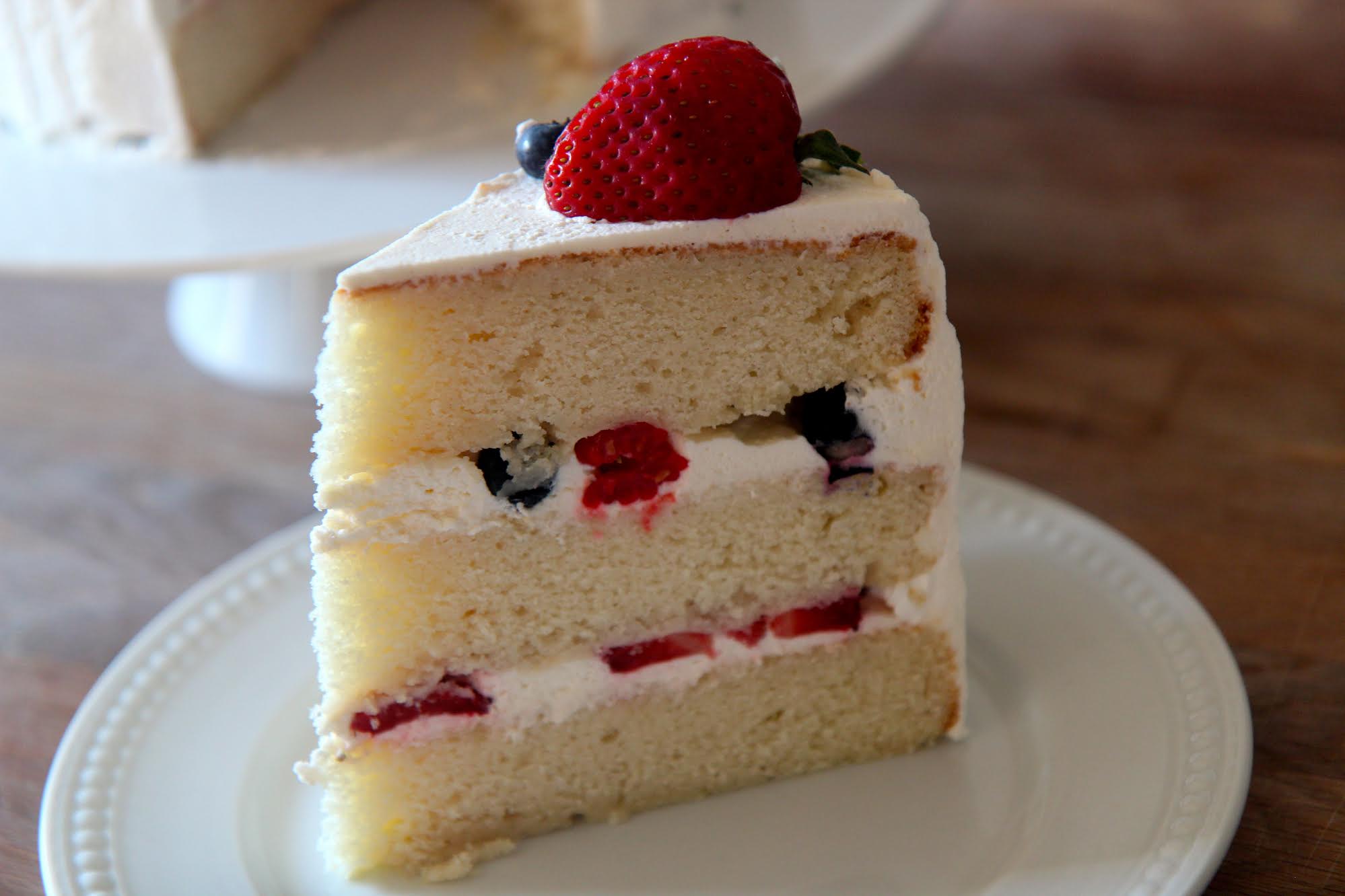 Three layers of yellow cake with a sweet vanilla frosting and filled with raspberries, strawberries, and blueberries