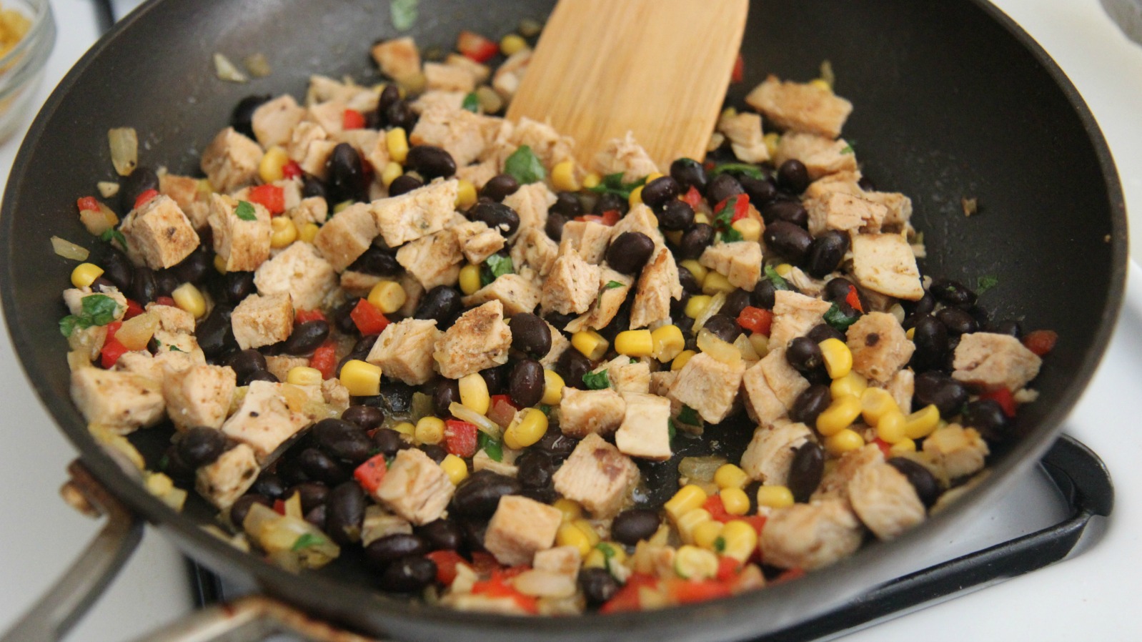 Mix the cubed chicken in with the beans, corn, pepper and more spices. Don't overcook or the chicken will become dry.