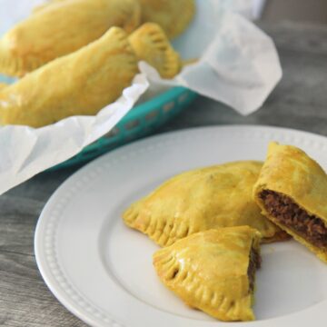 Jamaican beef patties in a basket and a white plate