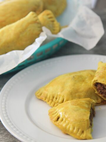 Jamaican beef patties in a basket and a white plate
