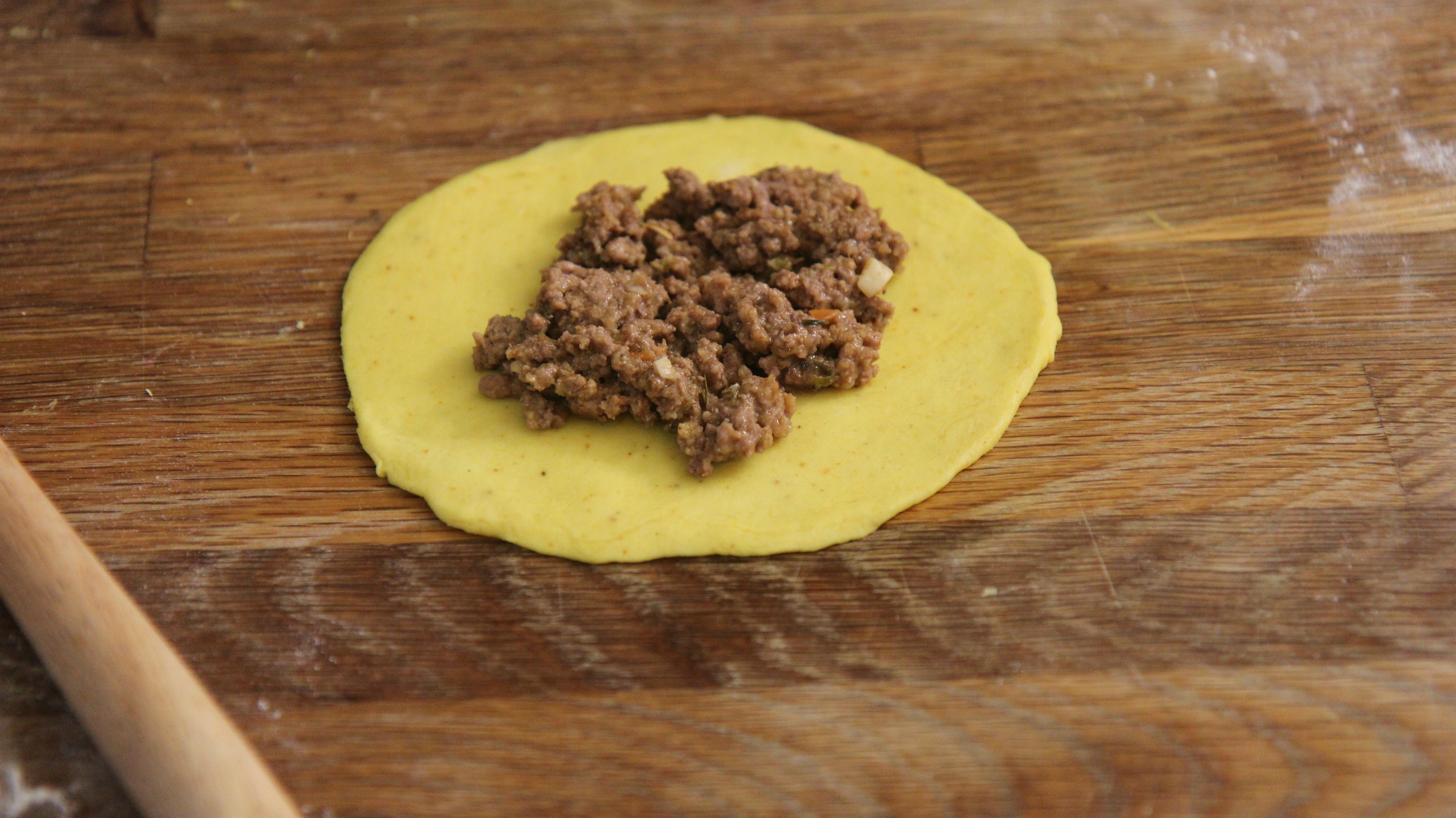 a disc of yellow dough with cooked ground beef. 