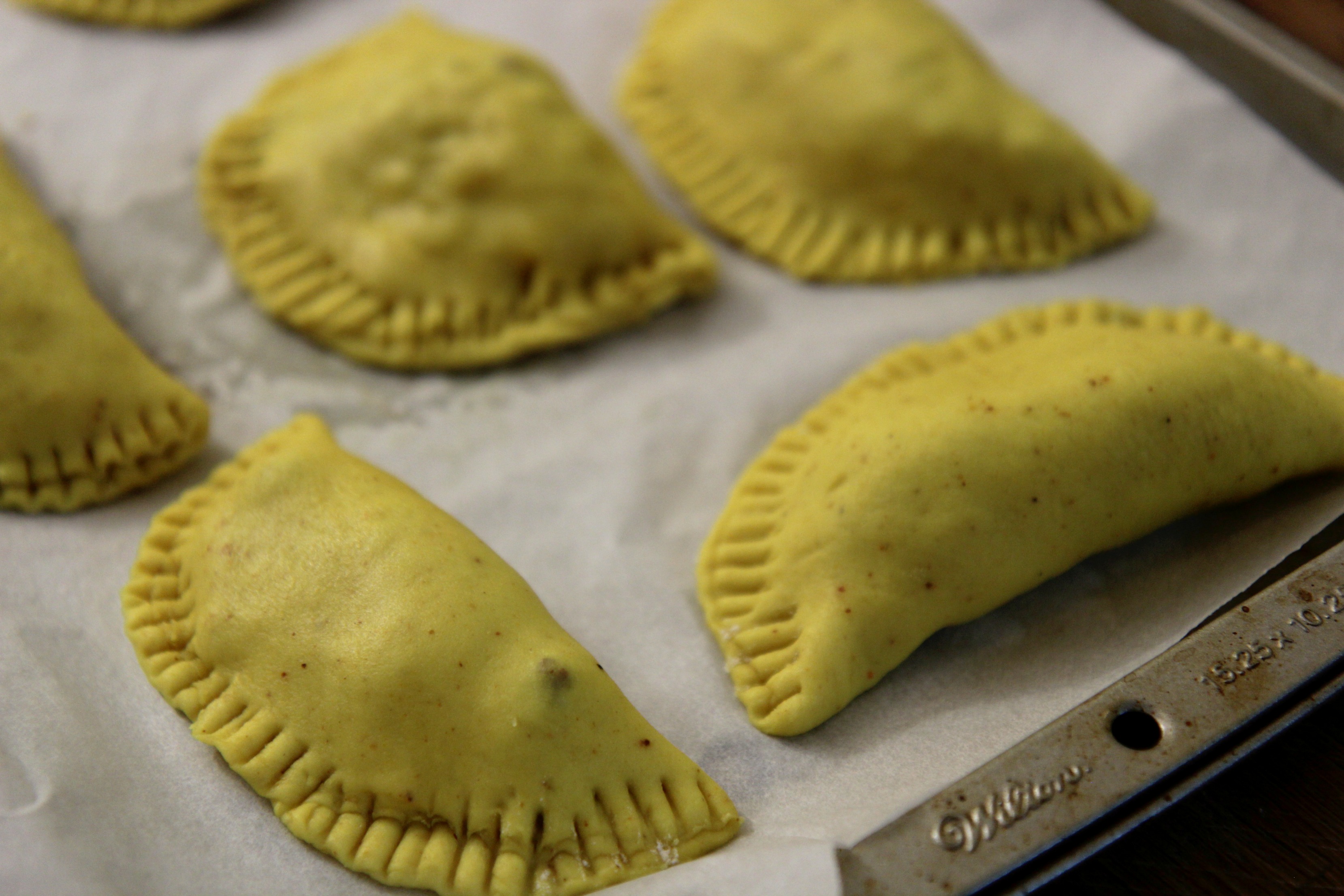 Jamaincan beef patties on a baking sheet. 