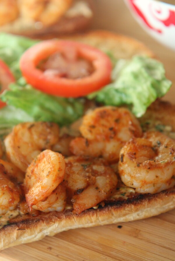 grilled shrimp po boy sandwich on a wooden board.