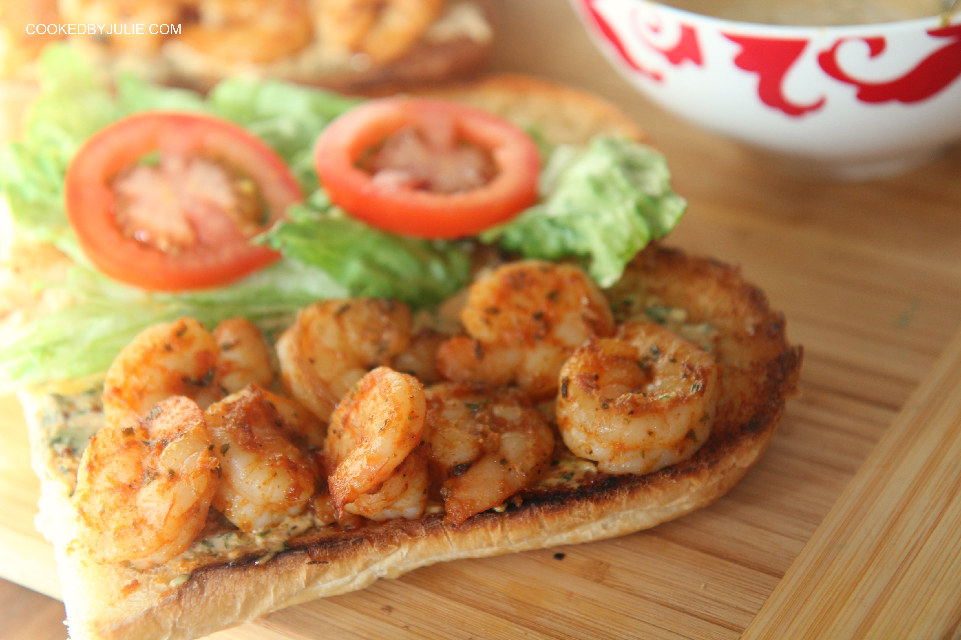 Grilled shrimp po'boy sandwich on a wooden board. 