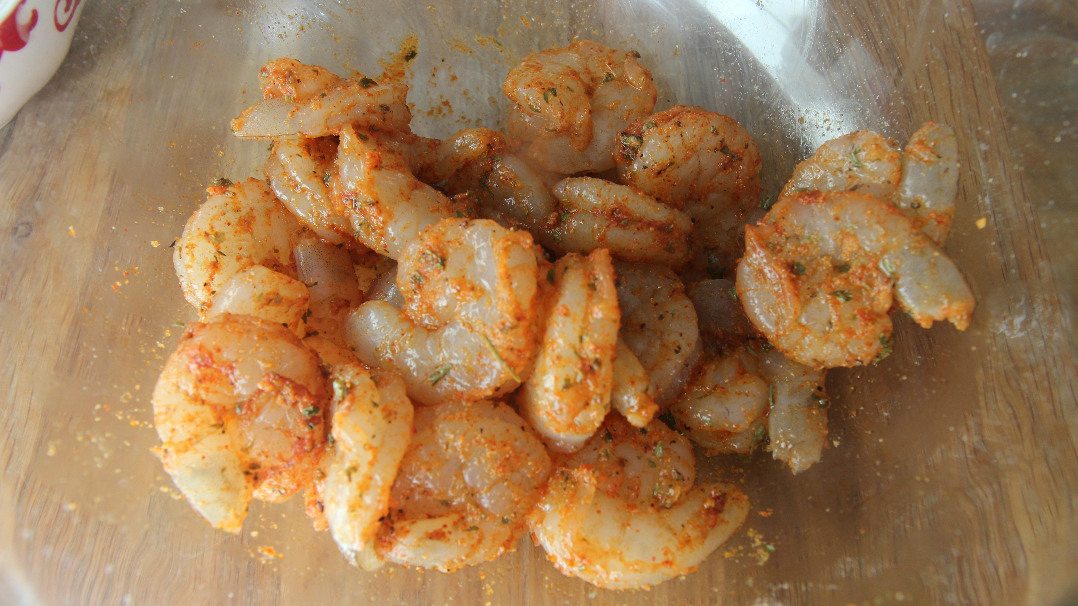 Marinated raw shrimp in a glass bowl. 