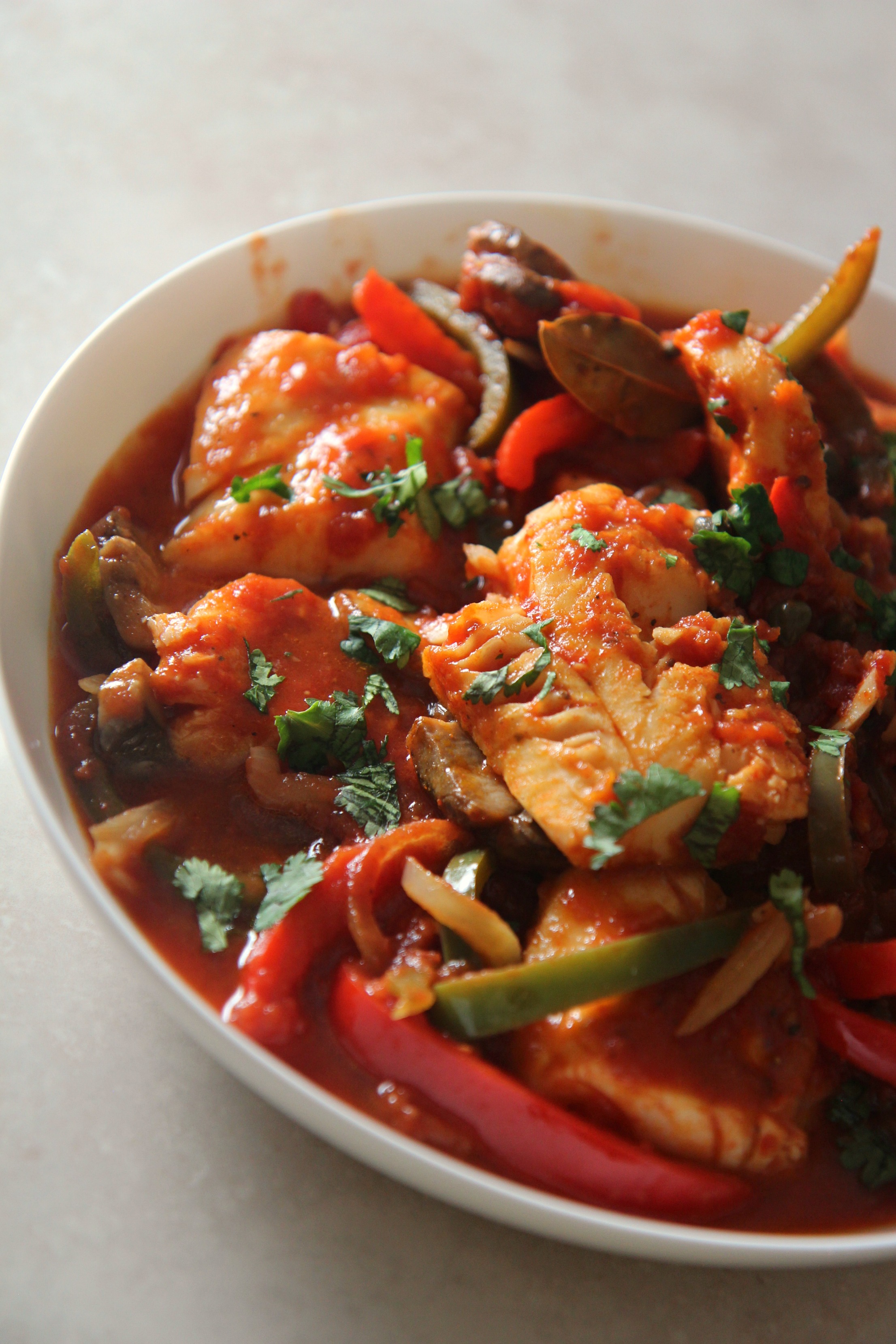 Delicious skillet cod dinner served in a bowl with tender red and green peppers, onions, and a herb garnish. 