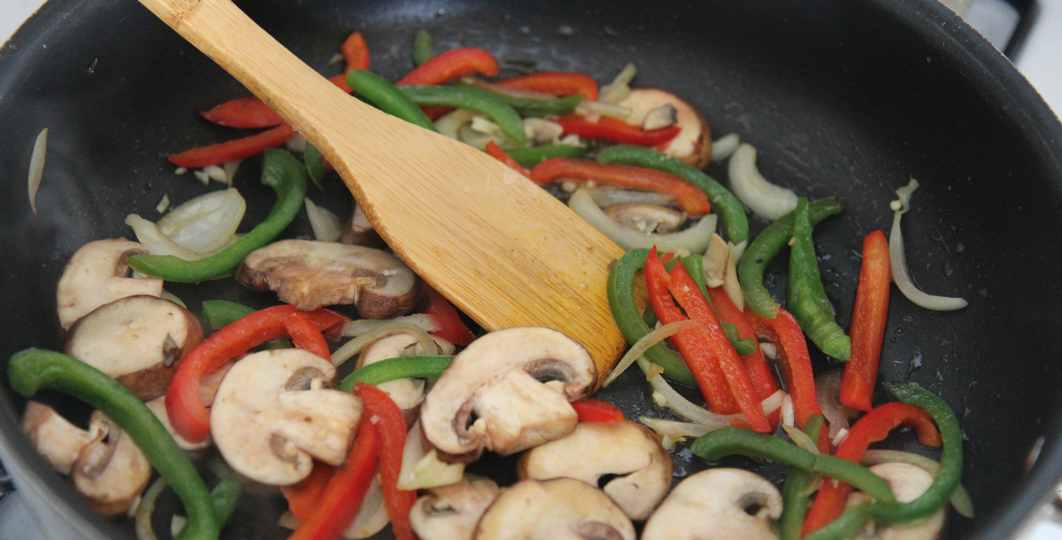 Saute the vegetables together in a skillet with some oil. Vegetables include mushrooms, onions, and red and green peppers. 