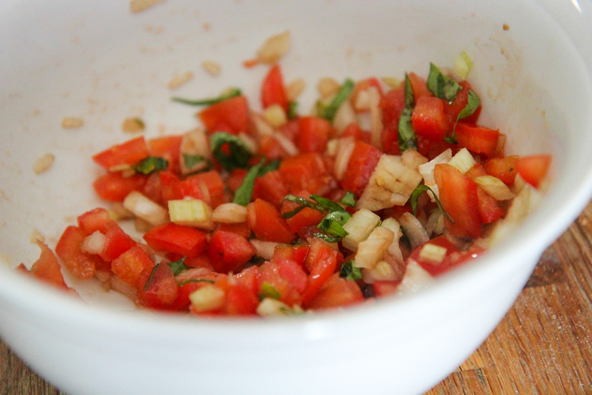 diced tomatoes, diced onions, and fresh sliced basil in a small white bowl.