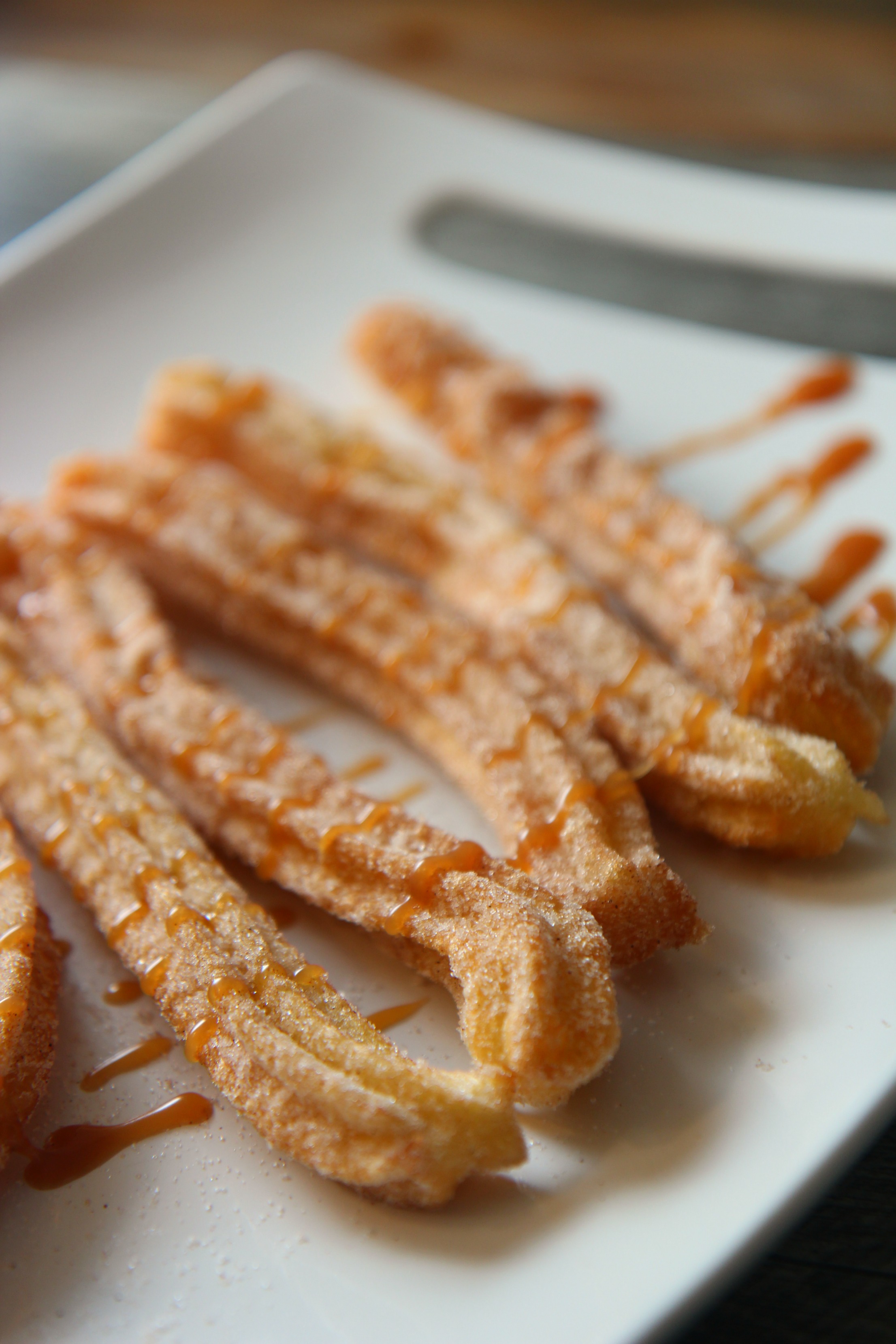 five churros on a white plate.