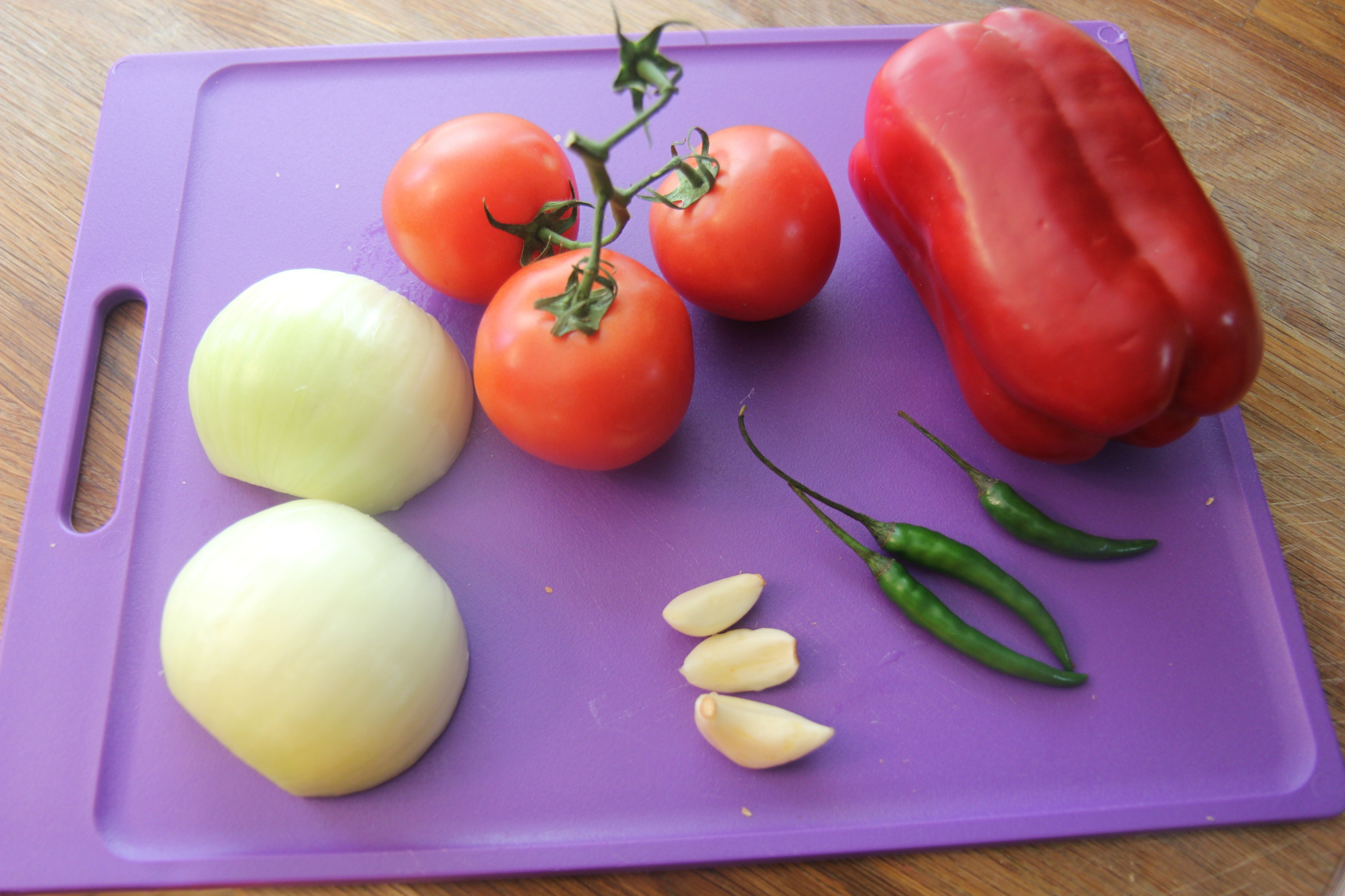 Spicy chicken tortilla soup ingredients on a purple cutting board.