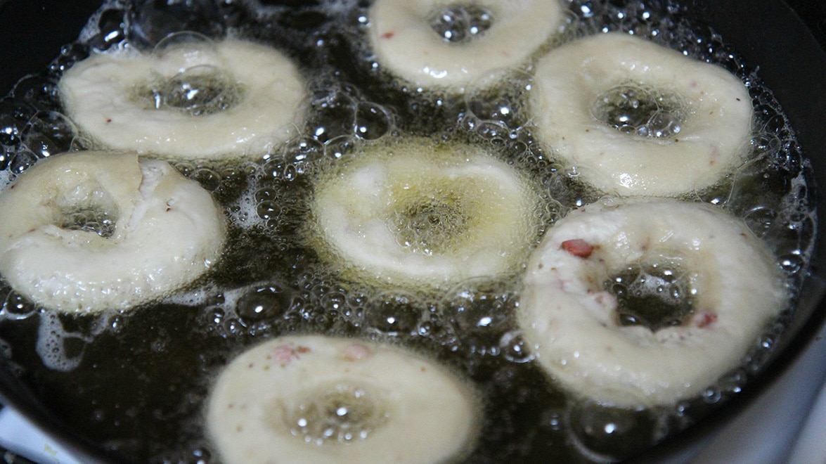 donuts frying in a skillet with oil. 