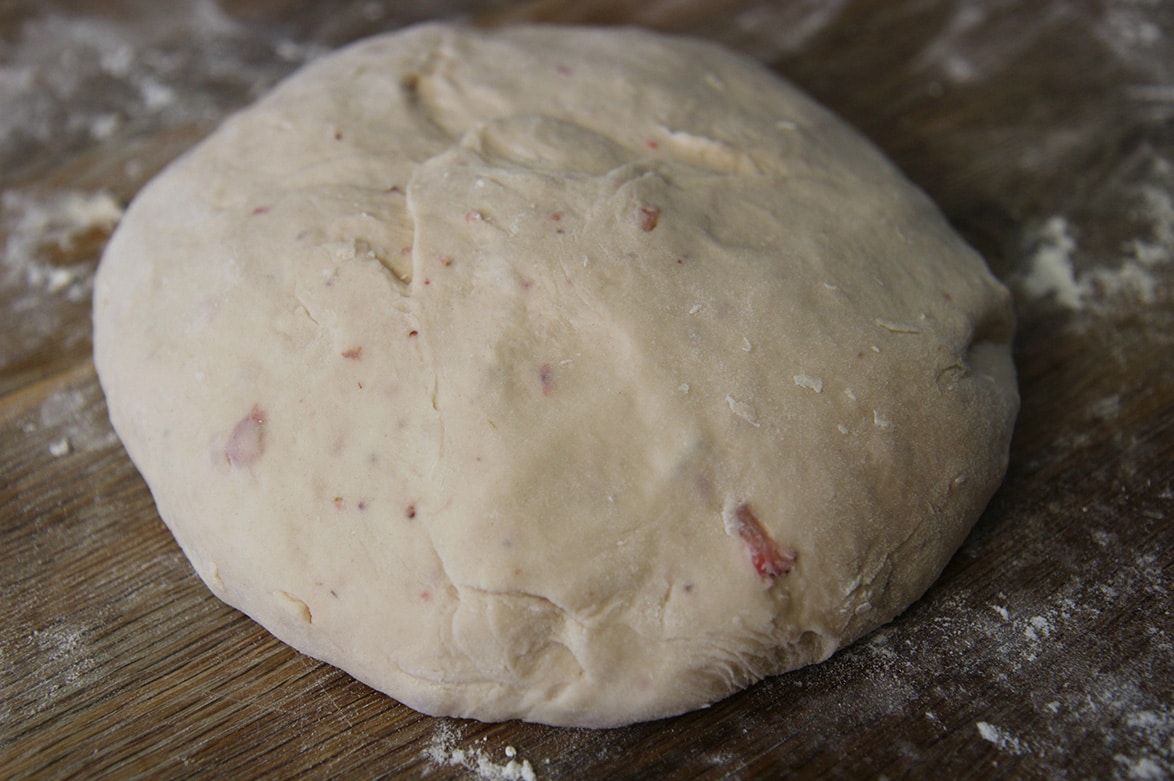 a ball of dough on a wooden floured surface.