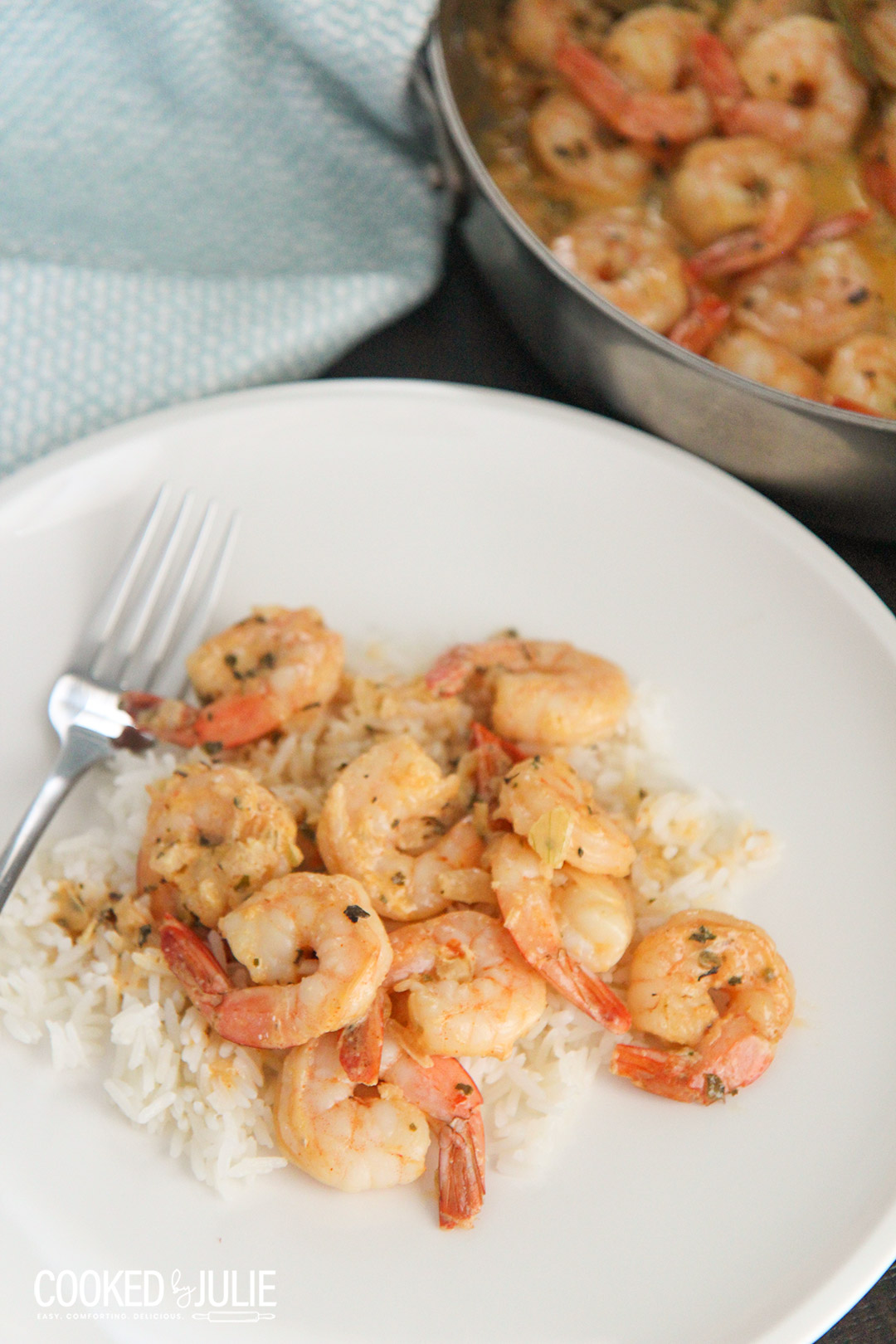shrimp over white rice on a white plate with a fork 