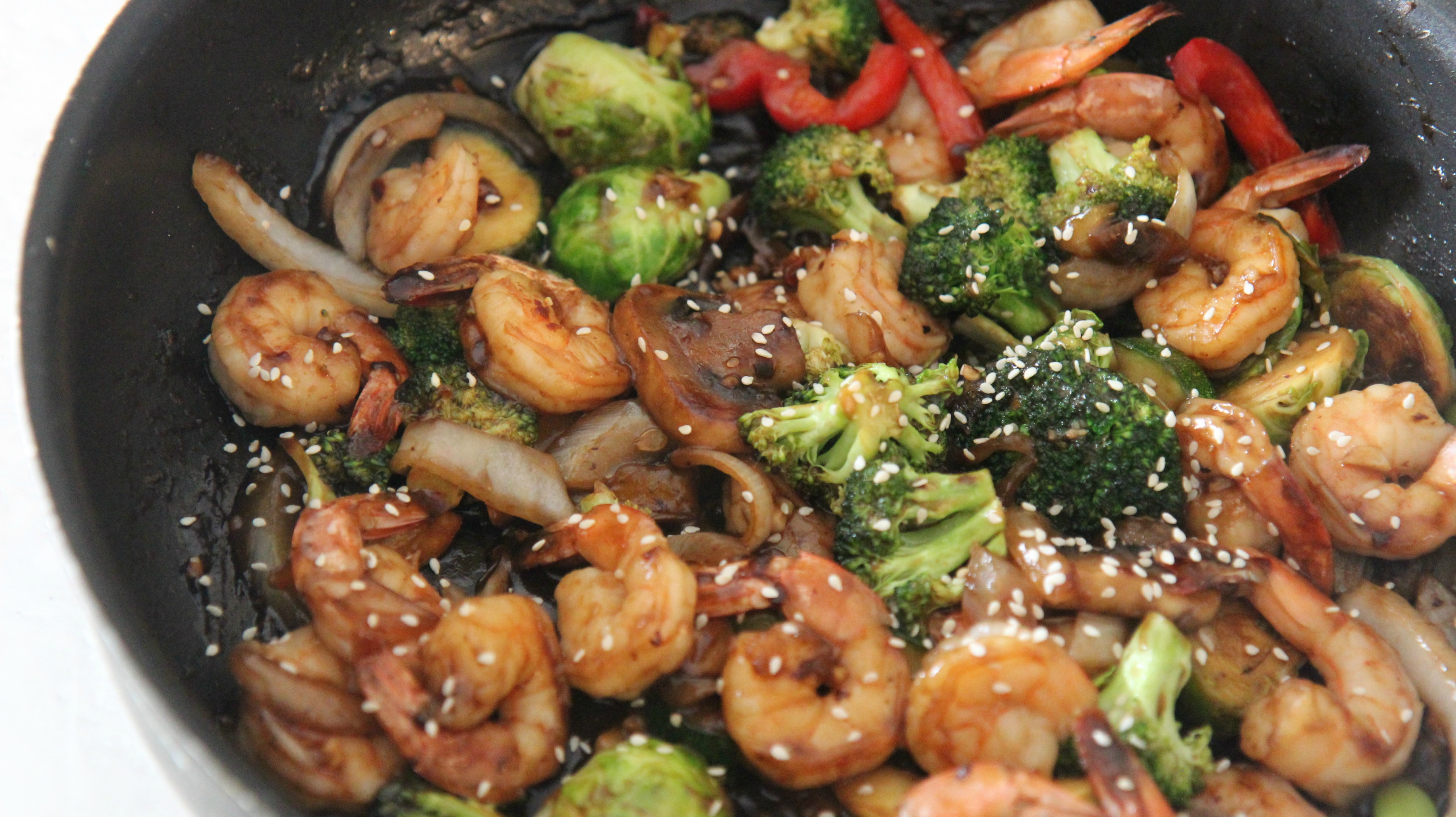 Shrimp and vegetable stir fry in a black skillet. 