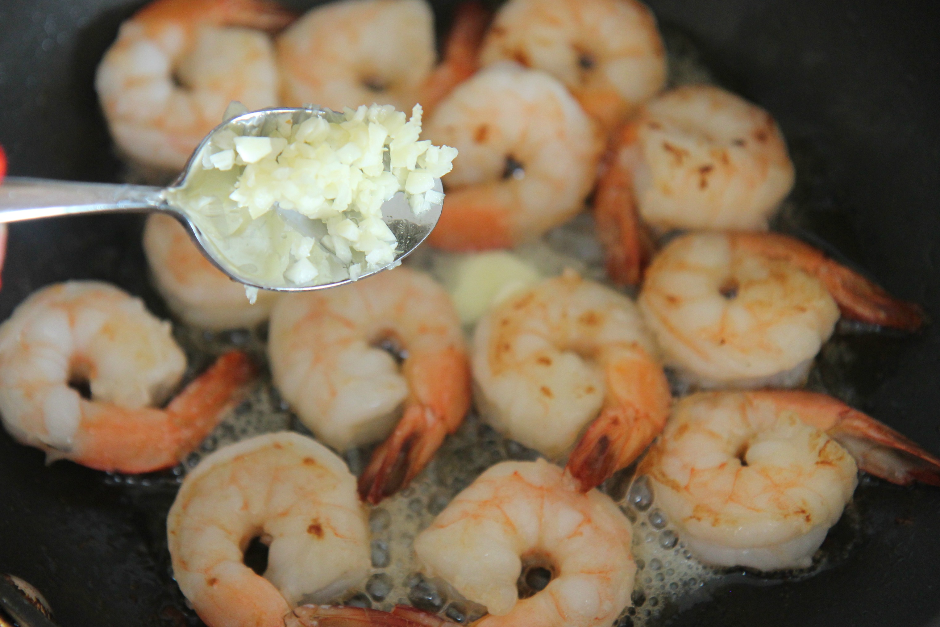 a spoon of fresh garlic and shrimp in a skillet. 