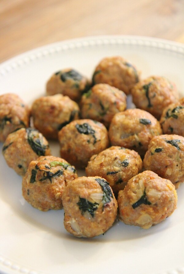 fifteen spinach and turkey meatballs on a white plate.