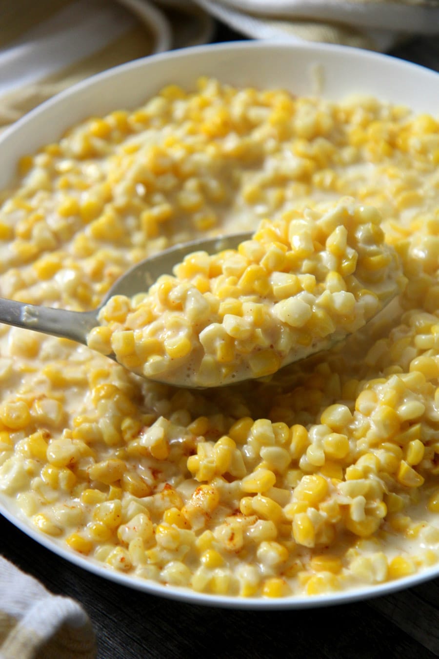 a spoon lifting creamed corn from a bowl.