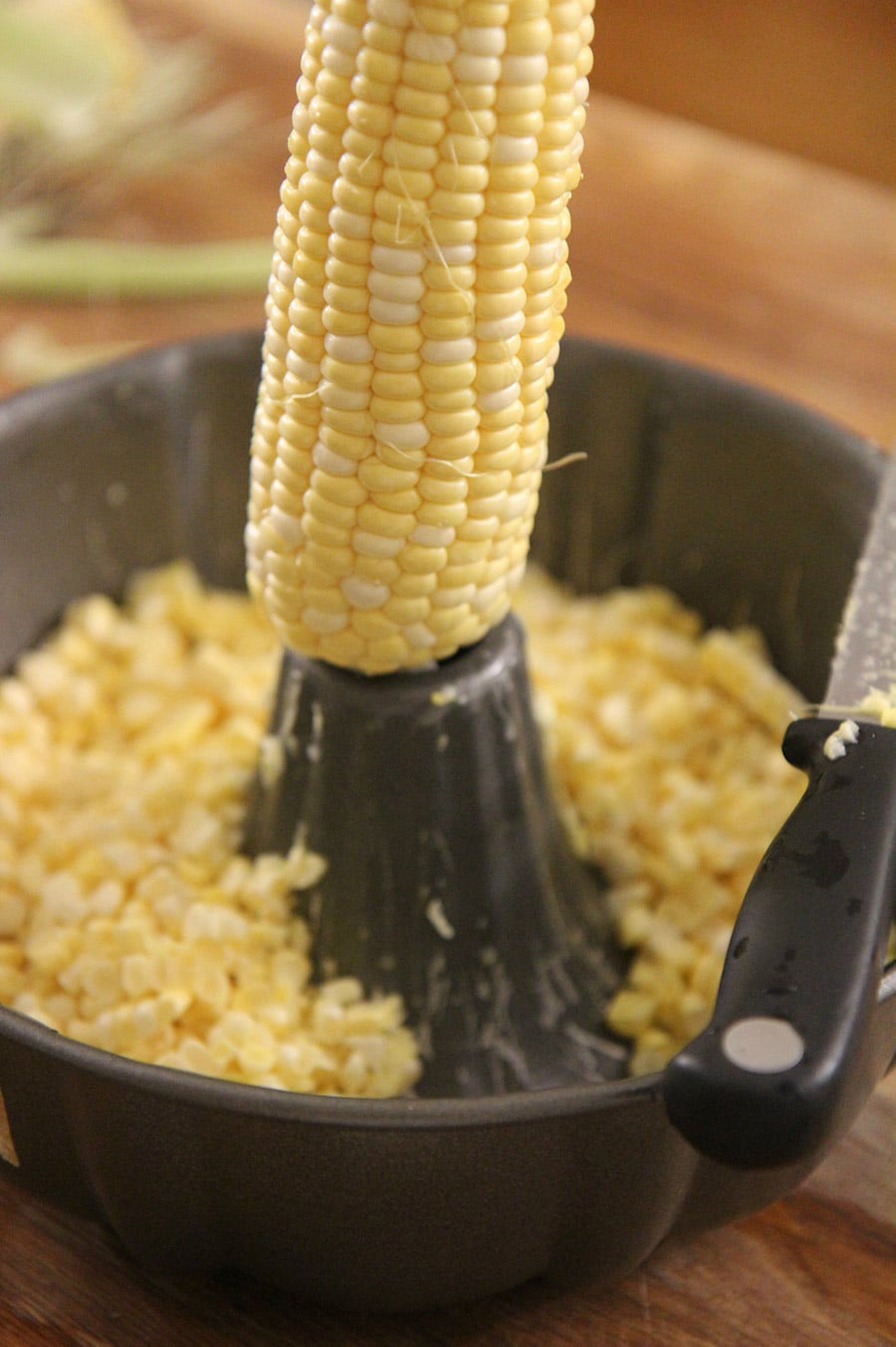 corn on the cob inside of a bundt pan with a knife.