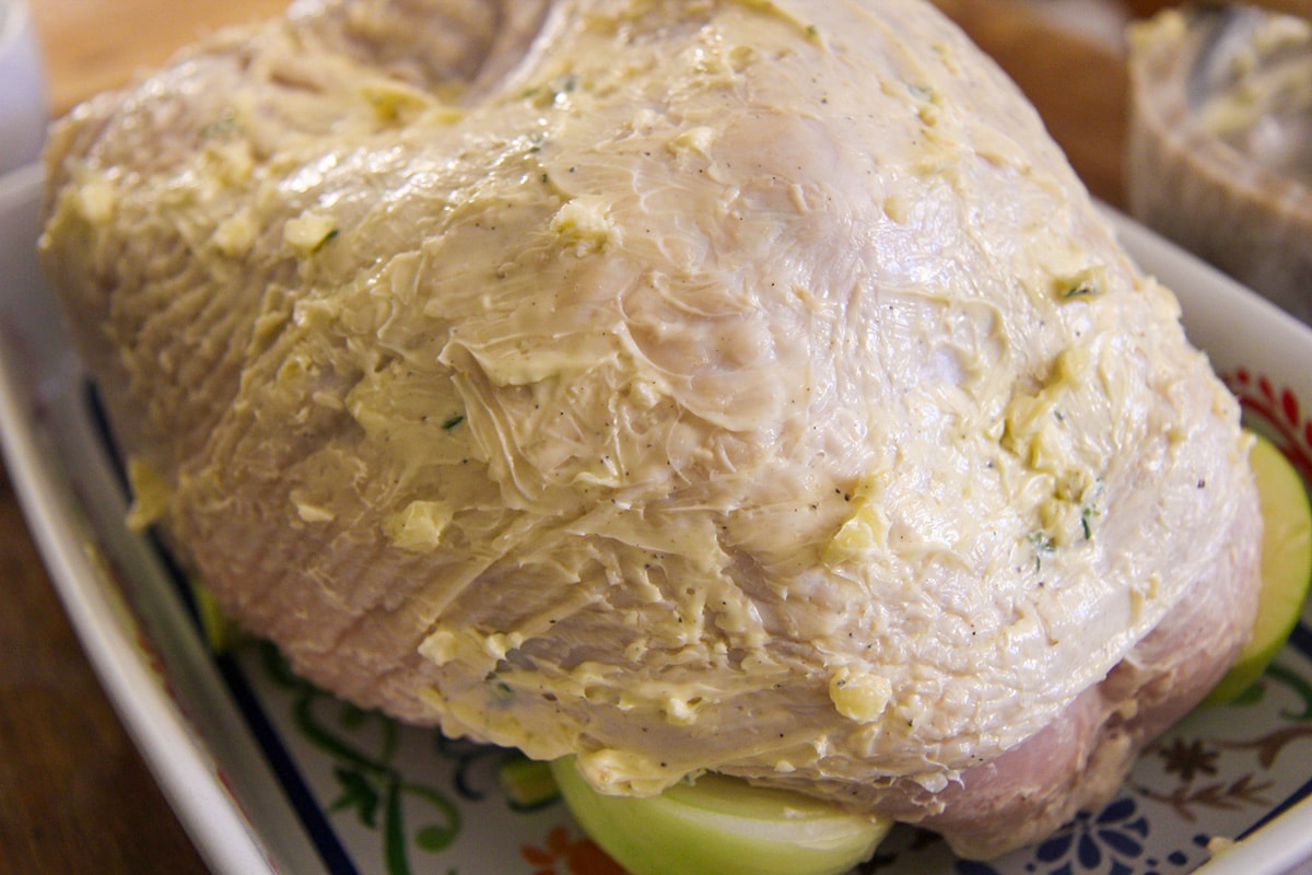 raw turkey breast with butter and garlic all over it. 