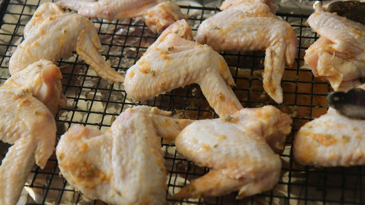 raw chicken marinated on a baking sheet.