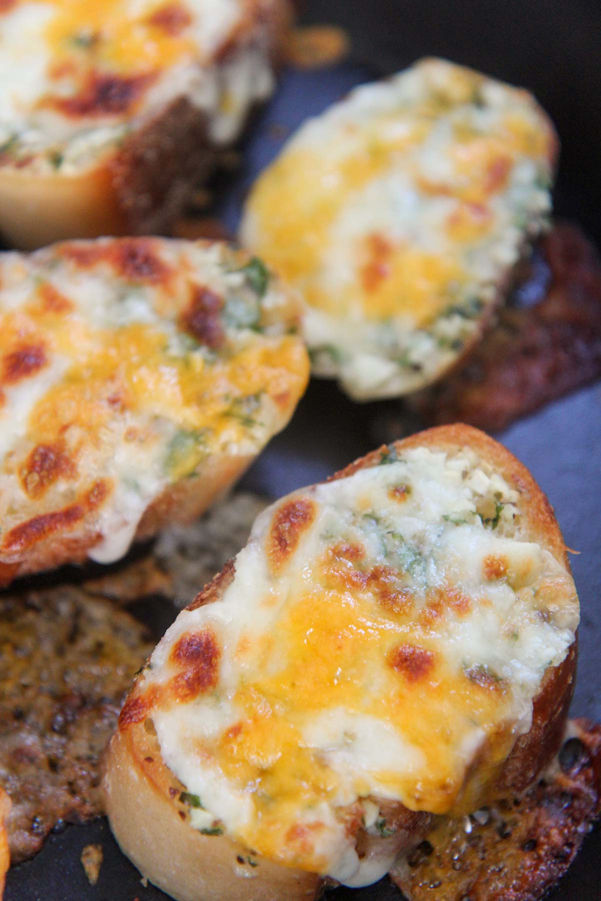 baked cheesy garlic bread slices up close.