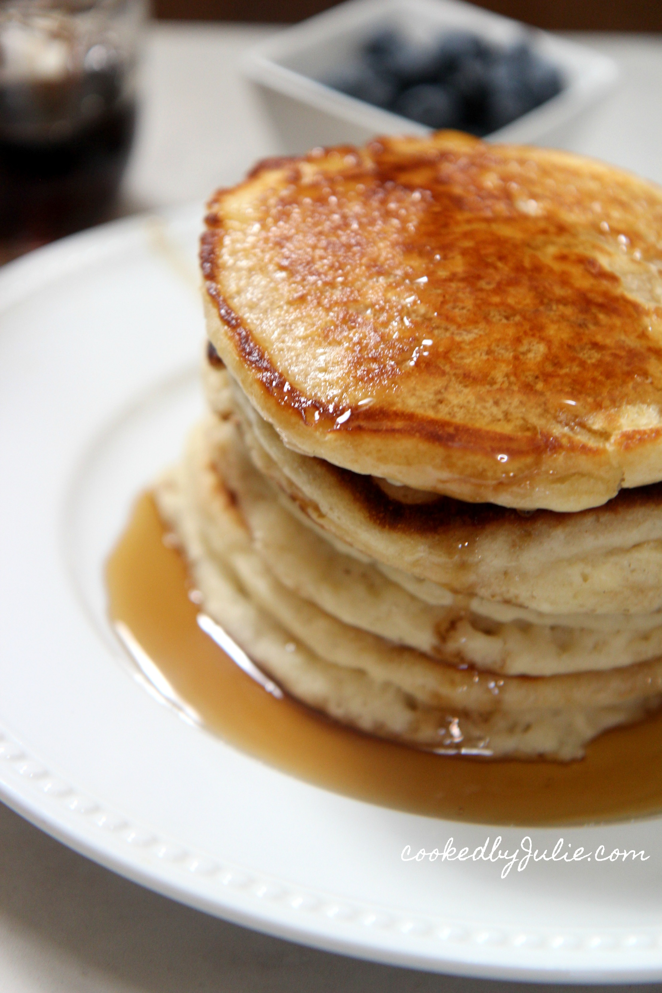 four pancakes on a white plate with maple syrup 