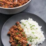 ground beef over white rice on top of a white plate
